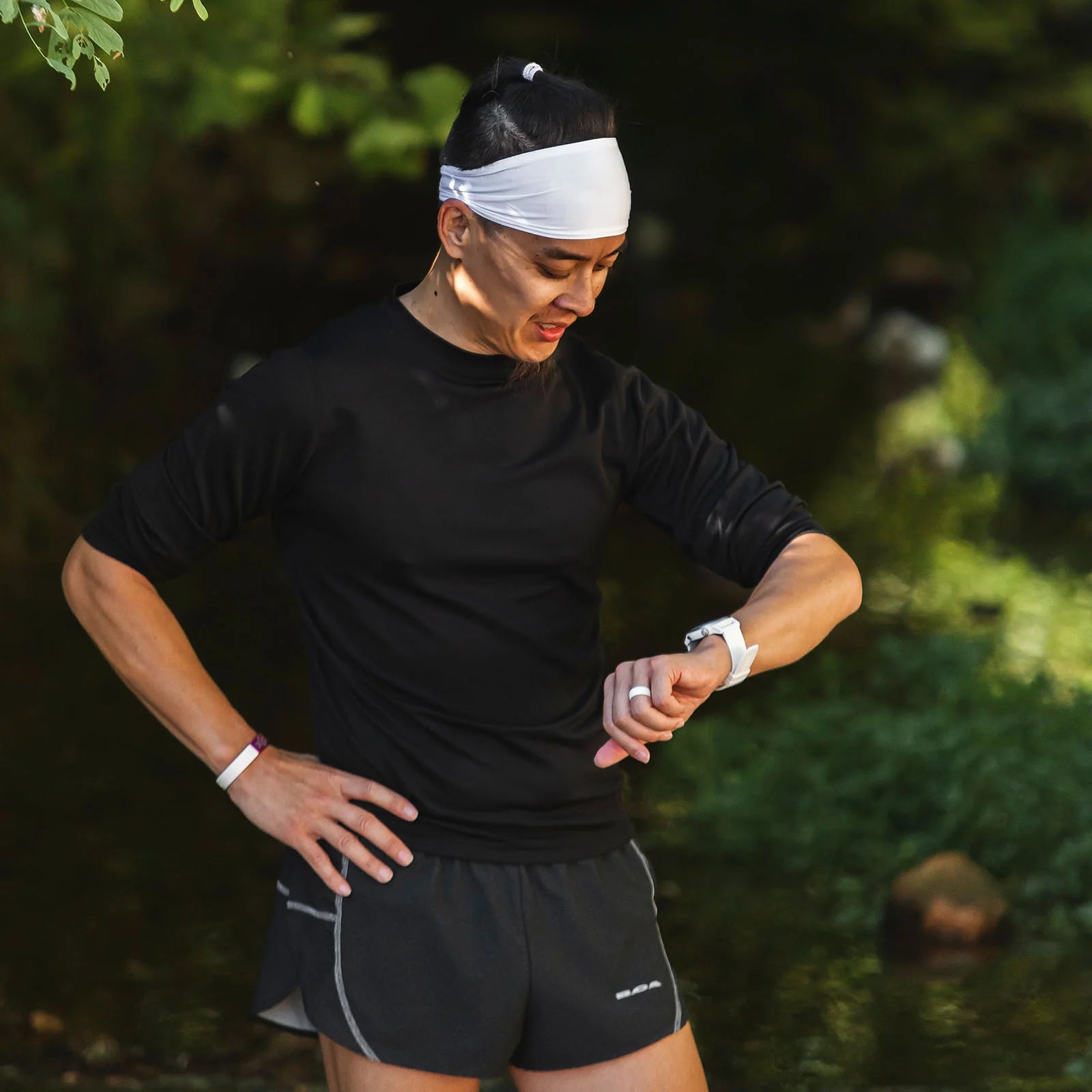 Runner checking a watch outdoors while wearing a performance headband